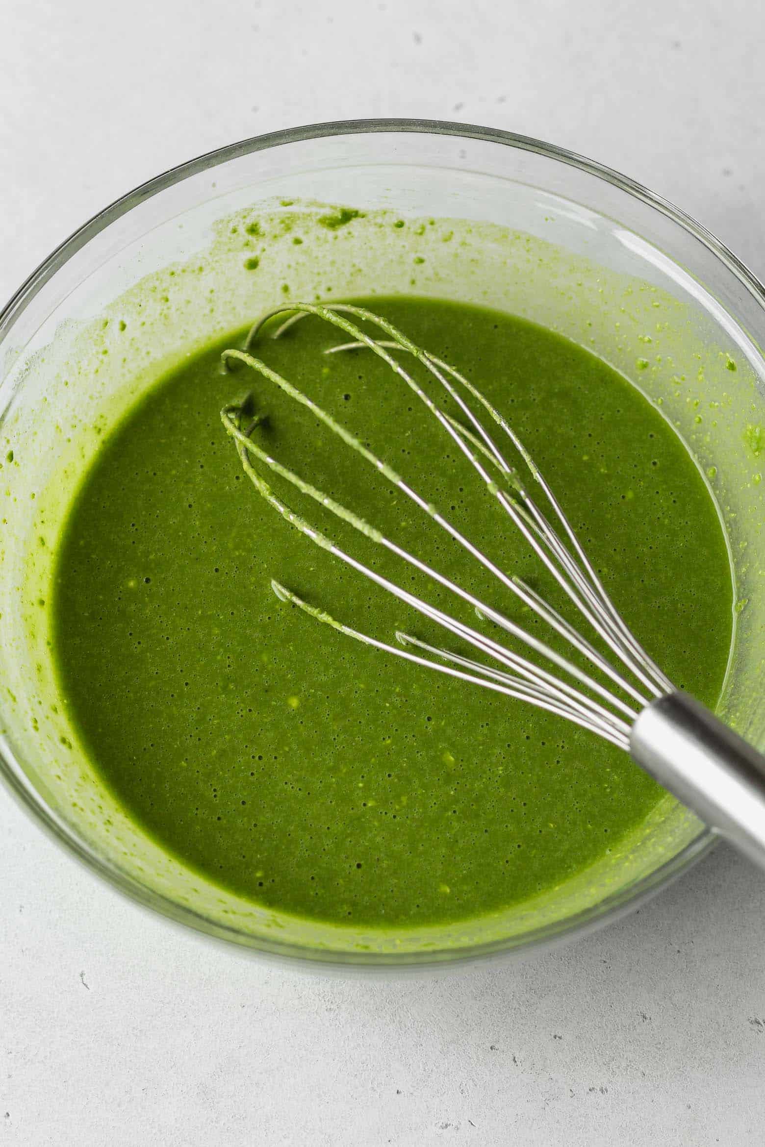 Bowl of matcha cake batter with a whisk