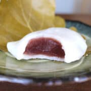 A square shot of kashiwa mochi with red bean filling with a bite taken out.
