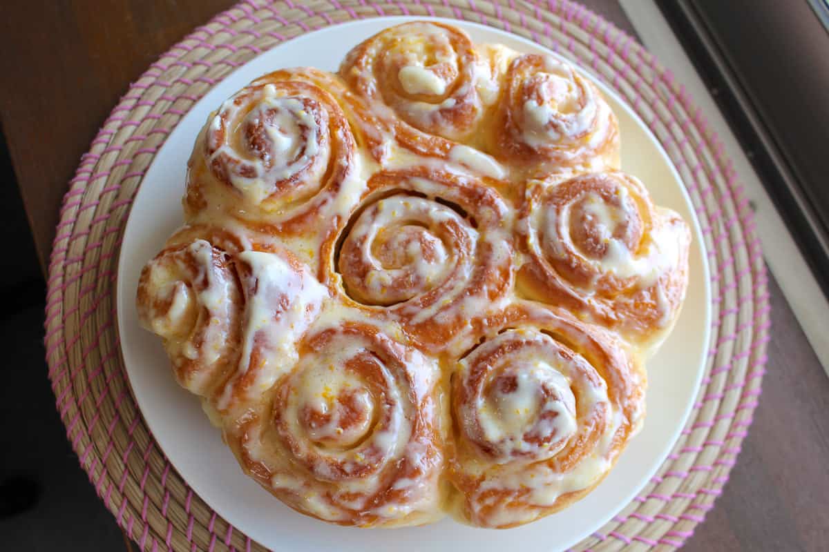 8 lemon rolls on a white plate with icing.