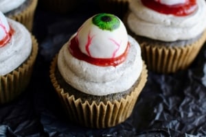 Halloween black sesame cupcakes are the perfect unique treat for an adult Halloween party! These Halloween eyeball cupcakes have a fluffy black sesame cake topped with black sesame buttercream frosting, topped with my Halloween white chocolate eyeballs! I added a spoonful of berry jam as fake blood, but I think mixing some black tahini with honey to make a spooky black goop would pair better in terms of taste. #halloween #halloweentreats #trickortreat #cupcake #cupcakes #blacksesame #kurogoma #sesame #cake #fluffy #black #spooky #creepy #dessert #halloweenparty #adult #eyeballs #whitechocolate #buttercream #frosting