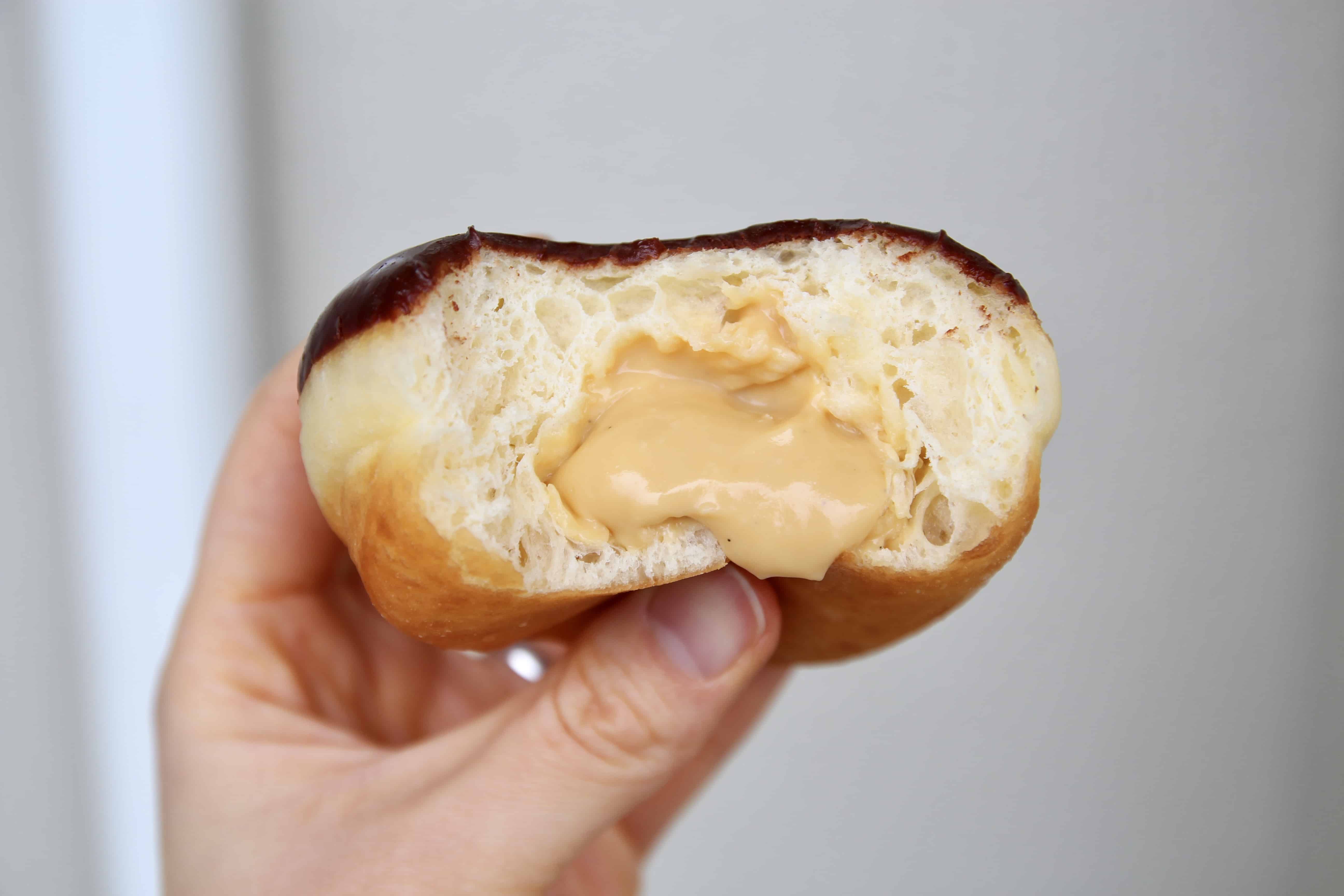 A bitten donut with custard filling and chocolate glaze