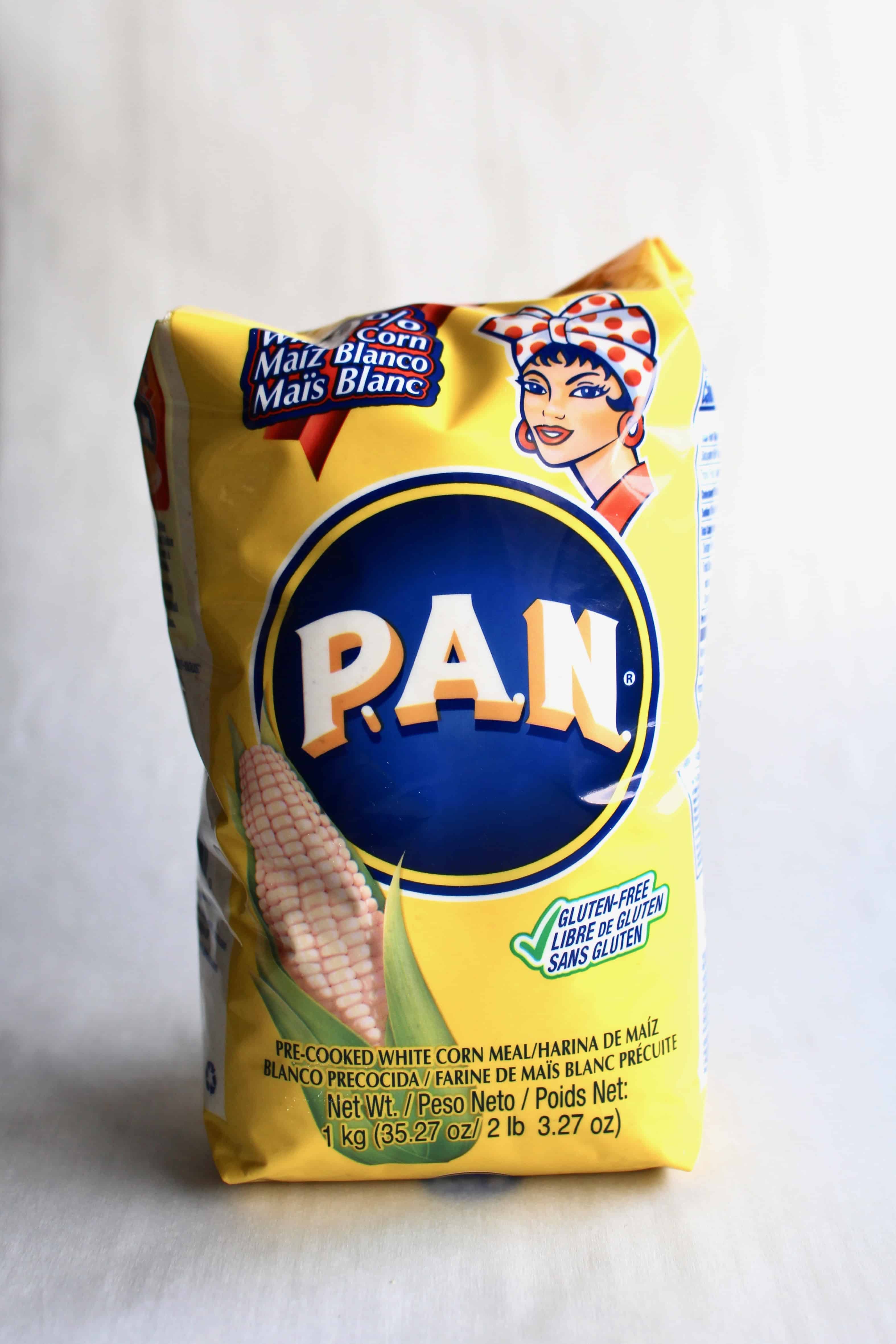 A yelow bag of harina PAN, also known as precooked cornmeal, in front of a white backdrop.