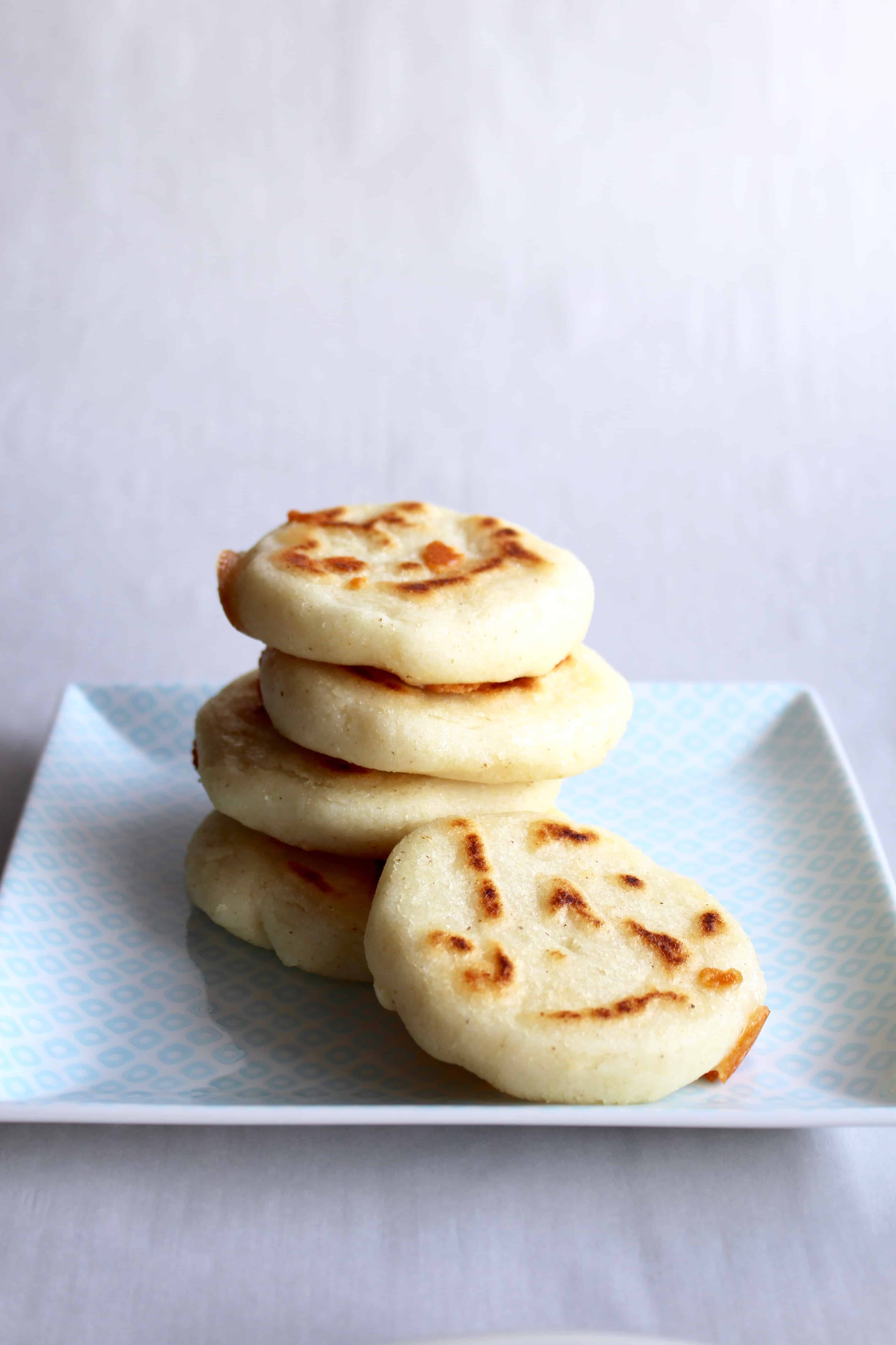 A stack of arepas on a square plate.