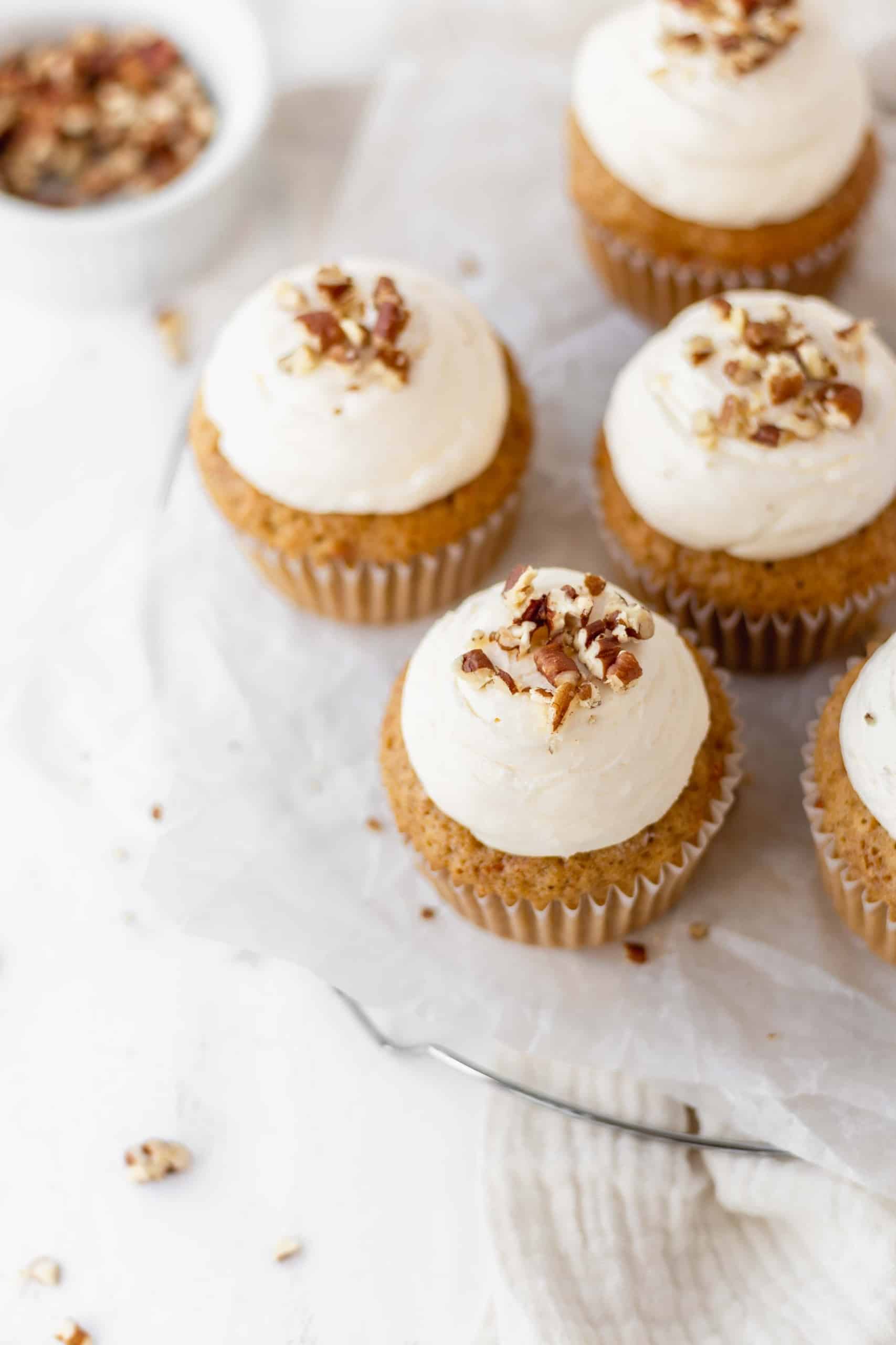 Cream cheese buttercream on carrot cupcakes with chopped pecans on top