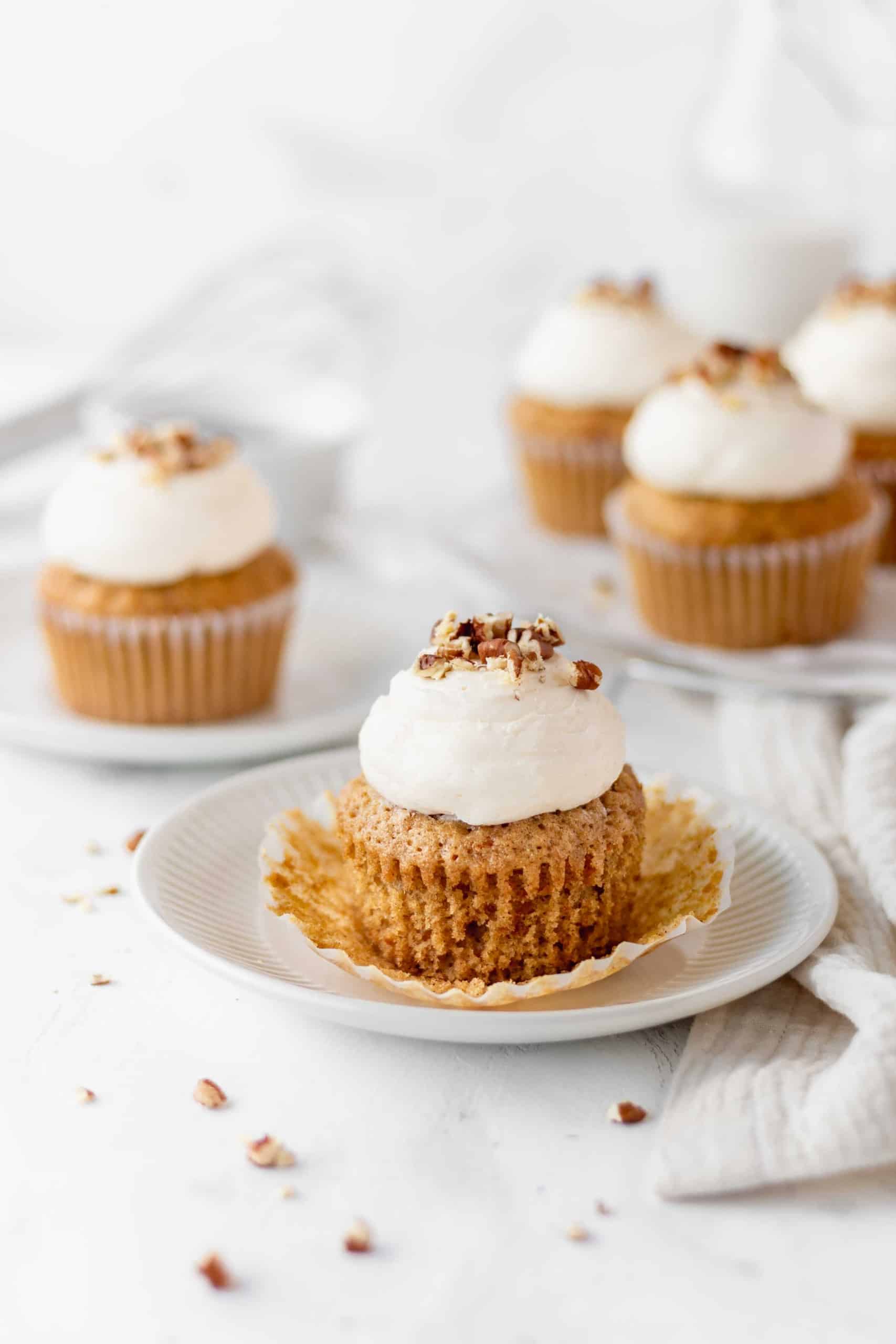 Carrot cake cupcake on a plate with the paper liner peeled