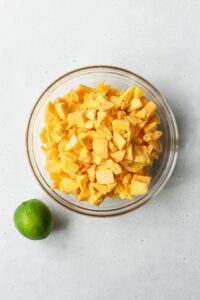 Frozen mango chunks in a bowl with a lime