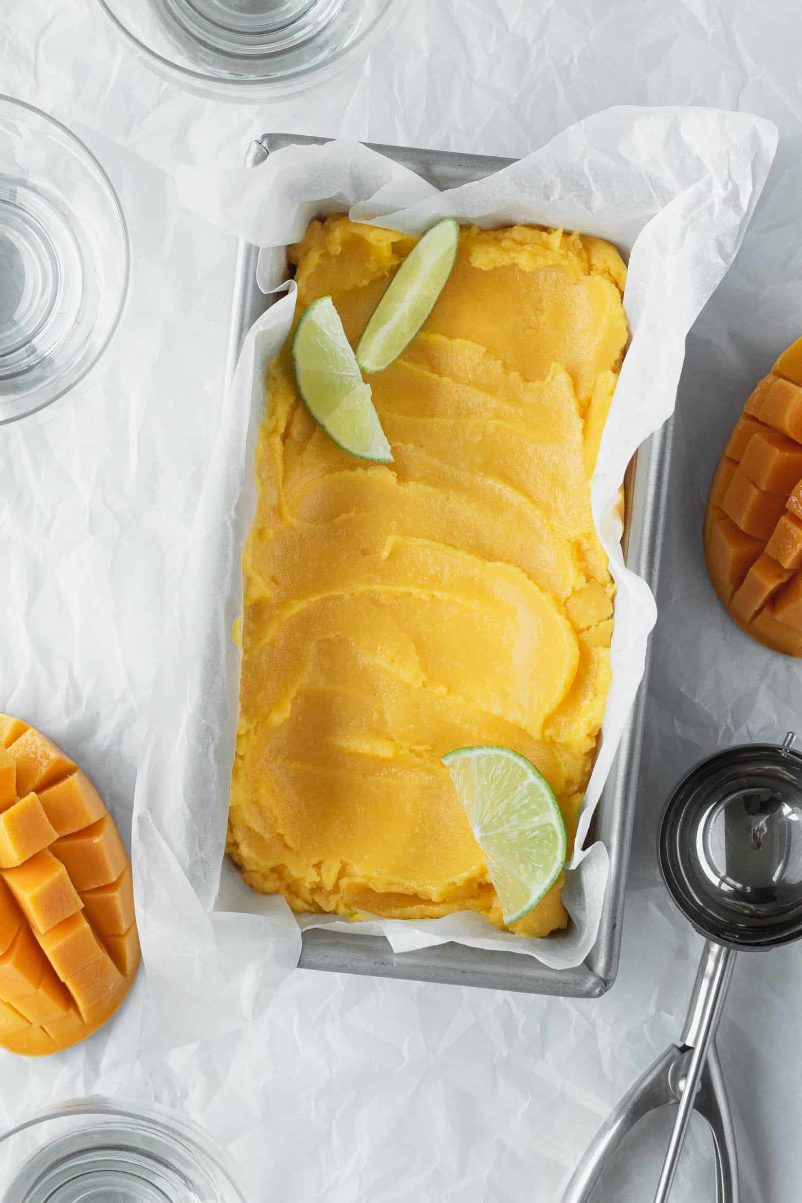 Mango sorbet in a loaf pan with lime wedges