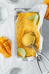 Mango lime sorbet in a pan with an ice cream scoop