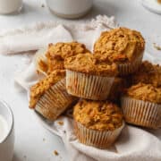 square image of a pile of healthy morning glory muffins on a white plate.