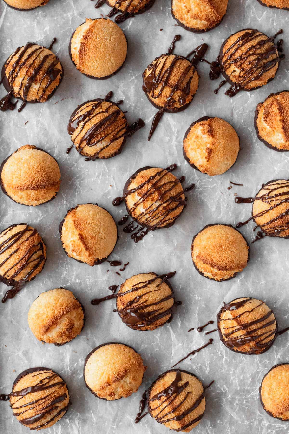 Vegan coconut macaroons with a chocolate drizzle on parchment paper.