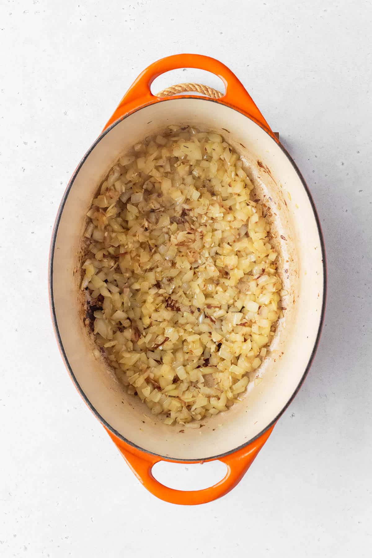 Minced onion and garlic cooking in a large enameled pot.