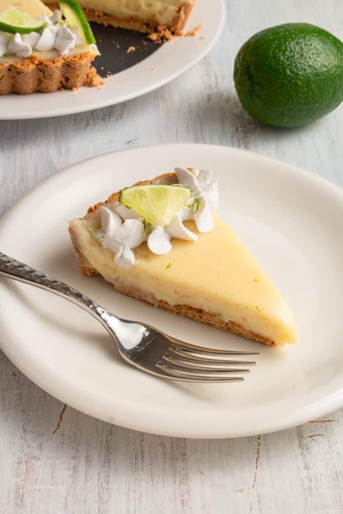 This vegan key lime pie is so creamy and tangy! With a crunchy graham cracker crust on the bottom and topped with rich coconut whipped cream, this plant based dessert won’t have you missing the traditional key lime pie! #vegandessert #vegankeylimepie #keylimepie #nobakedessert #nobakepie #plantbaseddessert