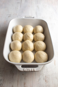 Put the balls of bread dough into a greased pan for a second rise