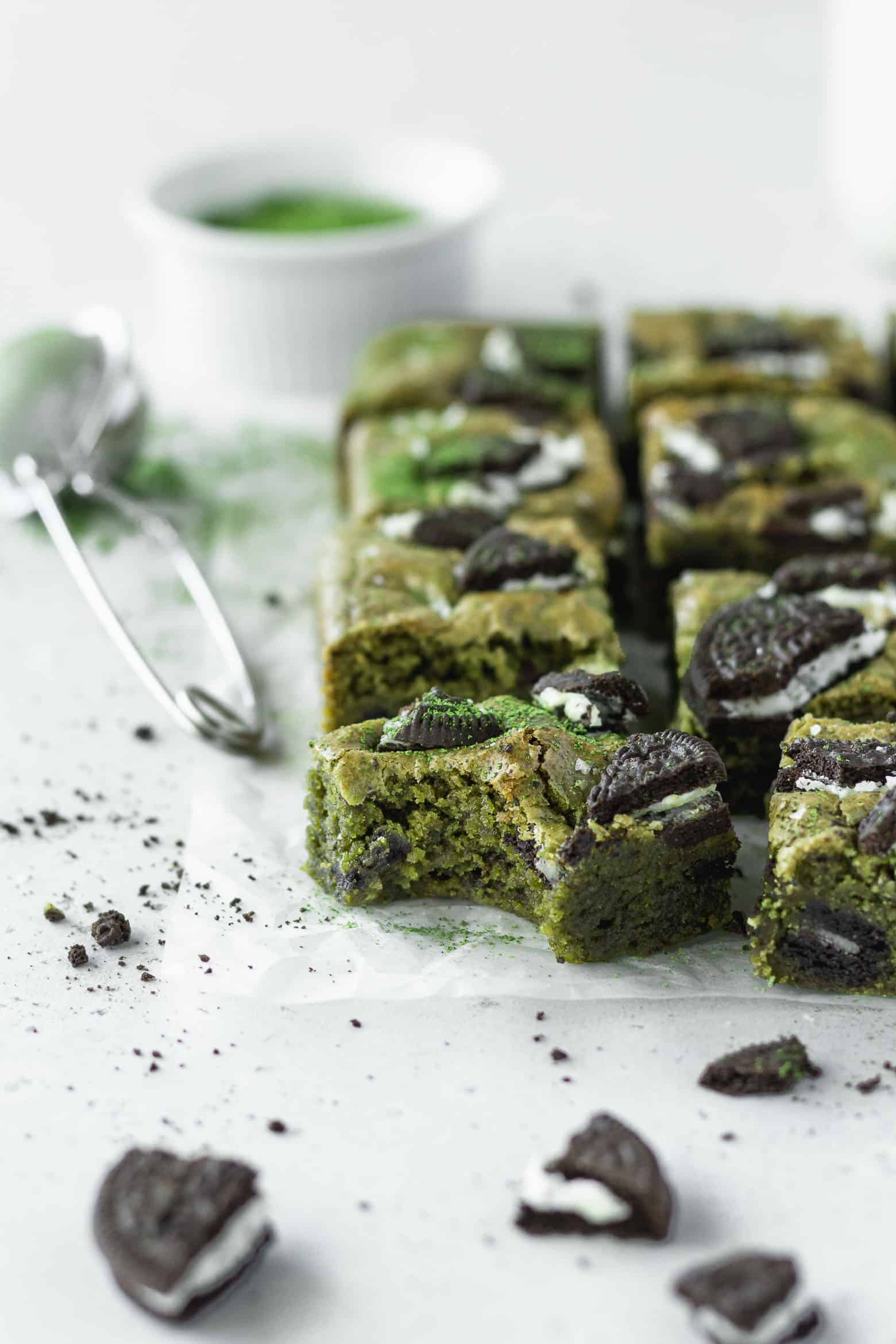 A bitten square of matcha blondie with Oreos