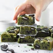 A hand reaching for a stack of matcha blondies