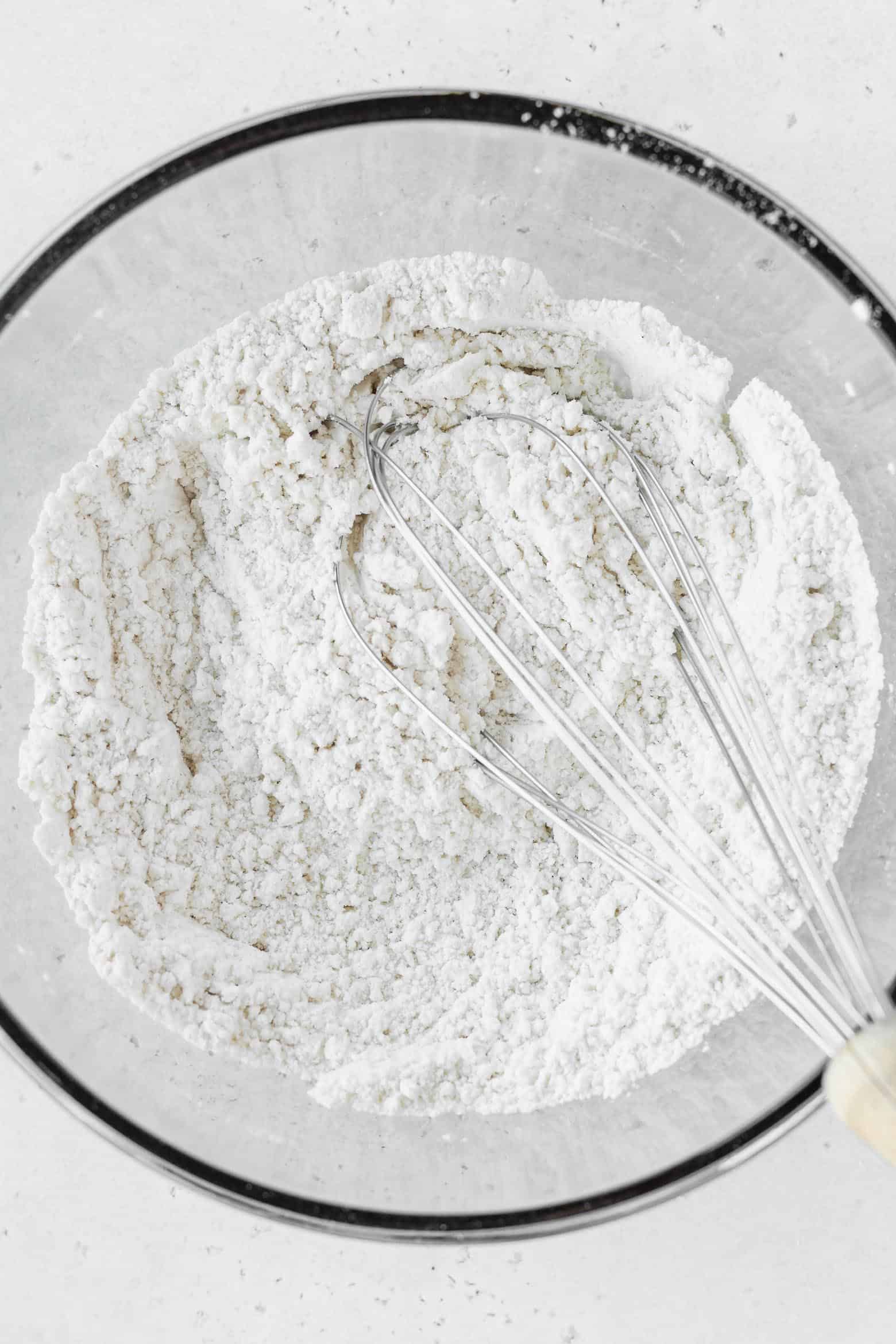 A bowl of flour and a whisk.