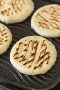 Arepas cooking on a grill