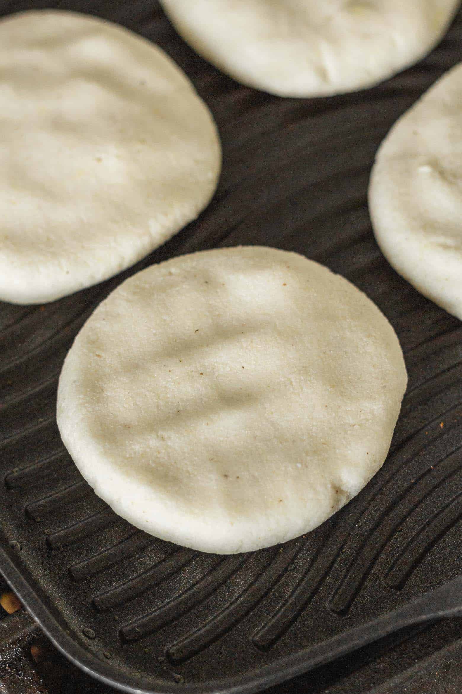 Uncooked arepas on a grill