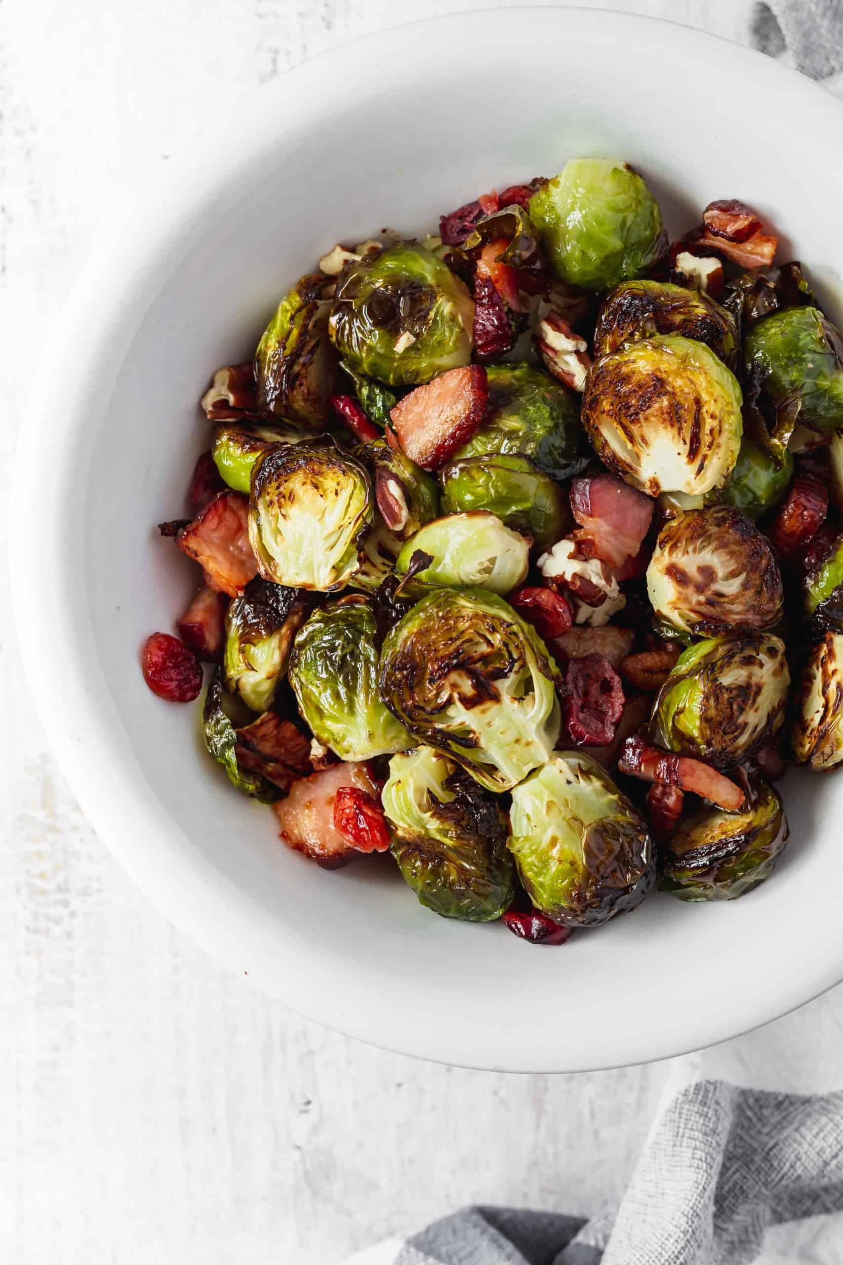 Brussels sprouts that don't suck and are actually delicious! Brussels sprouts are roasted with bacon, dried cranberries, and pecans. #roastedbrusselssprouts #brusselssprouts #thanksgivingsidedish #thanksgivingdinner #sprouts