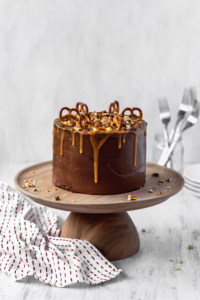 Frosted chocolate cake with peanuts and pretzels on a cake stand