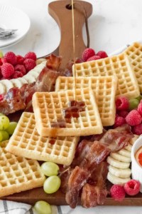 Maple syrup drizzled on waffles on breakfast board