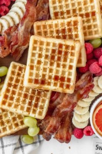 Waffles on a breakfast charcuterie board drizzled with maple syrup