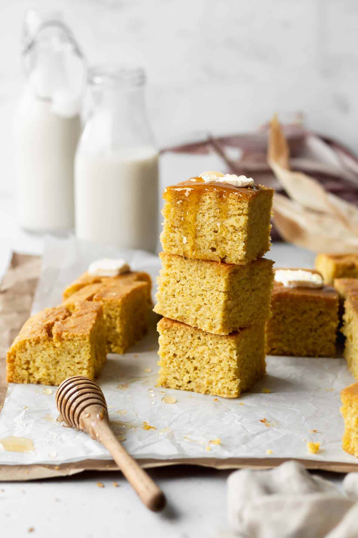 Stack of 3 pieces of gluten-free dairy-free cornbread with 2 jugs of milk in the background.
