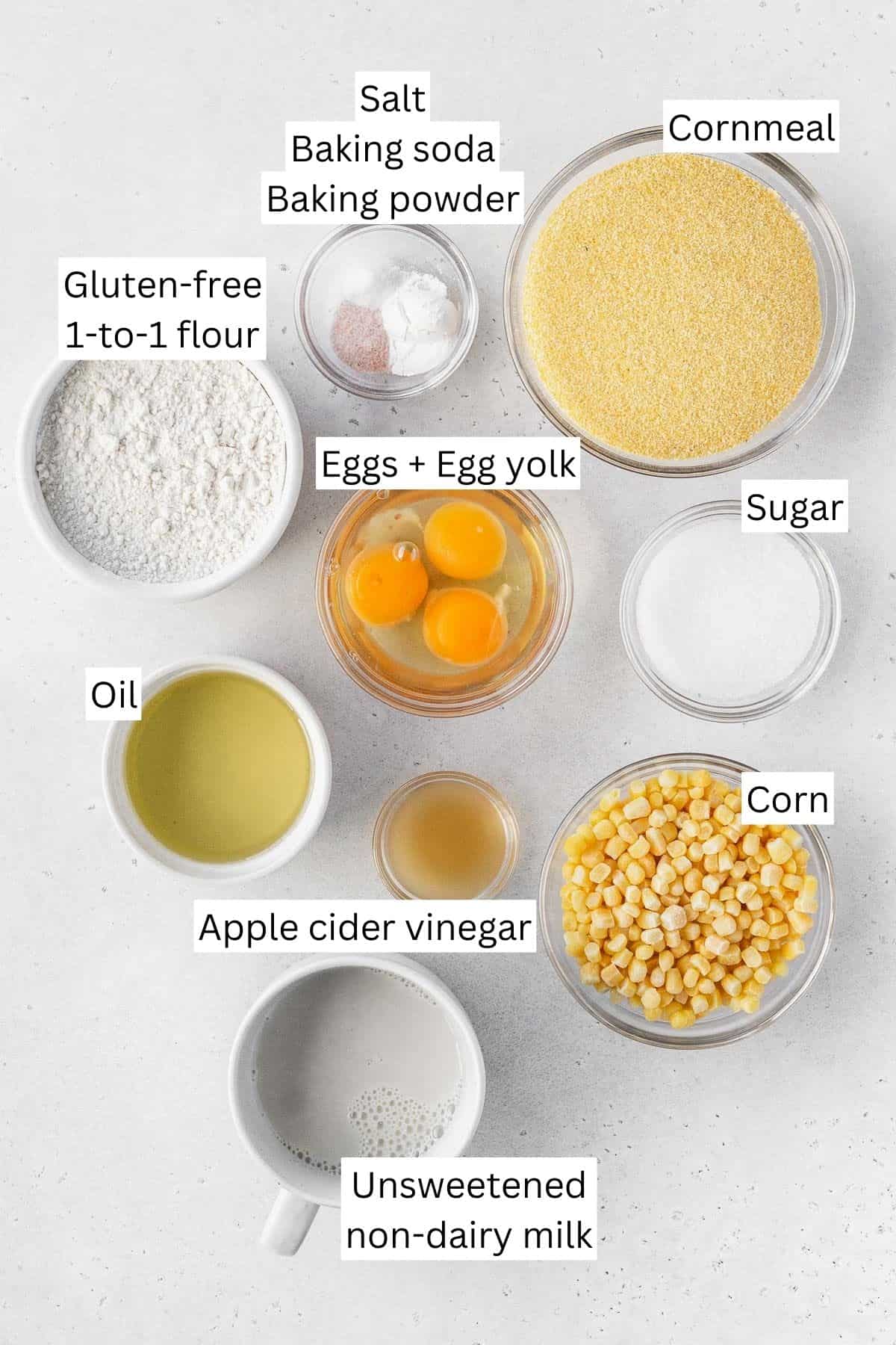 Ingredients for making dairy-free gluten-free cornbread measured out into bowls on a white table with text overlay.