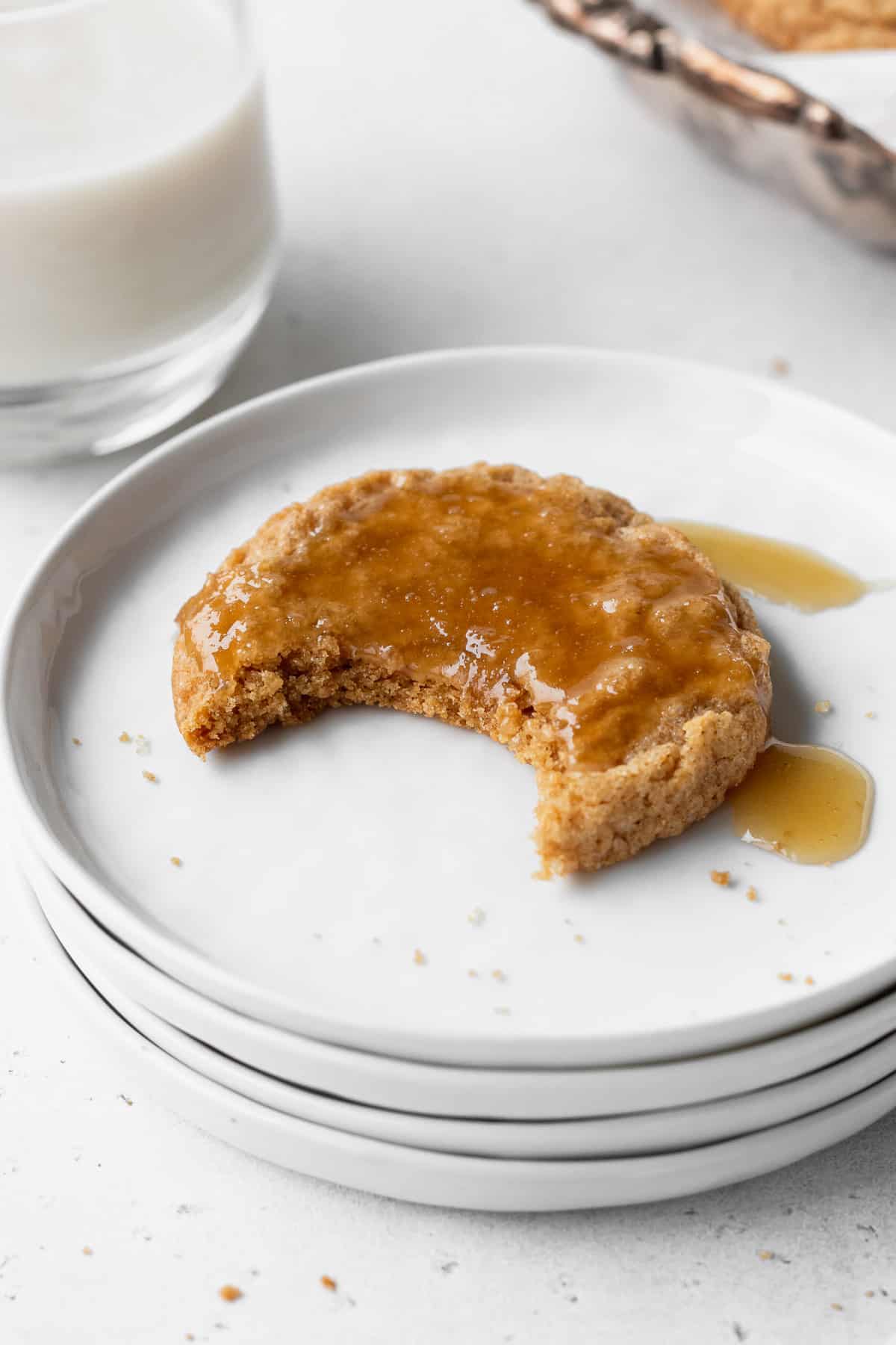 A bitten ginger cookie with a bite taken out on a white plate.
