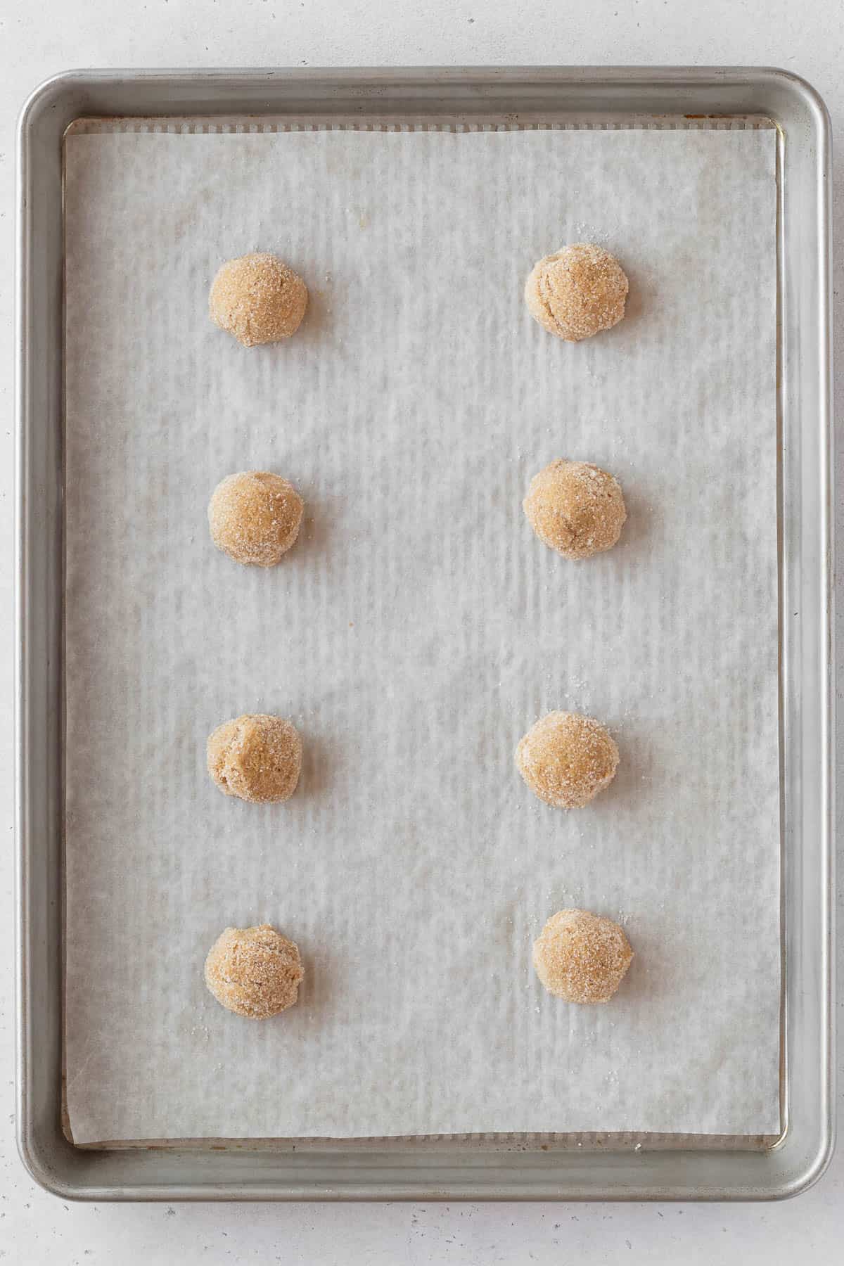 Cookie dough rolled into sugar and placed on a baking sheet.