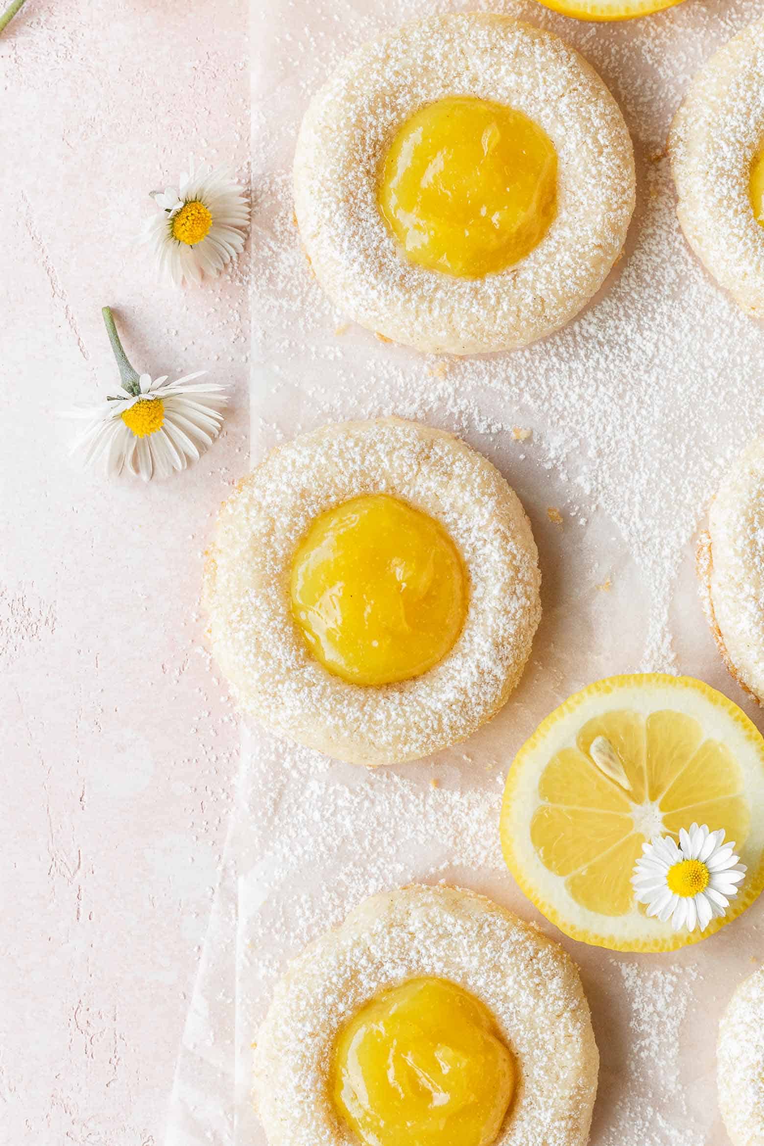 Vegan lemon thumbprint cookies on a pink surface.