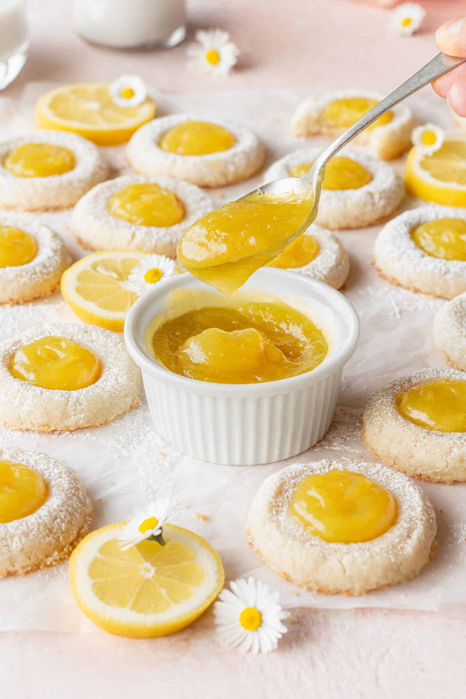 A dish of lemon curd with lemon thumbprint cookies