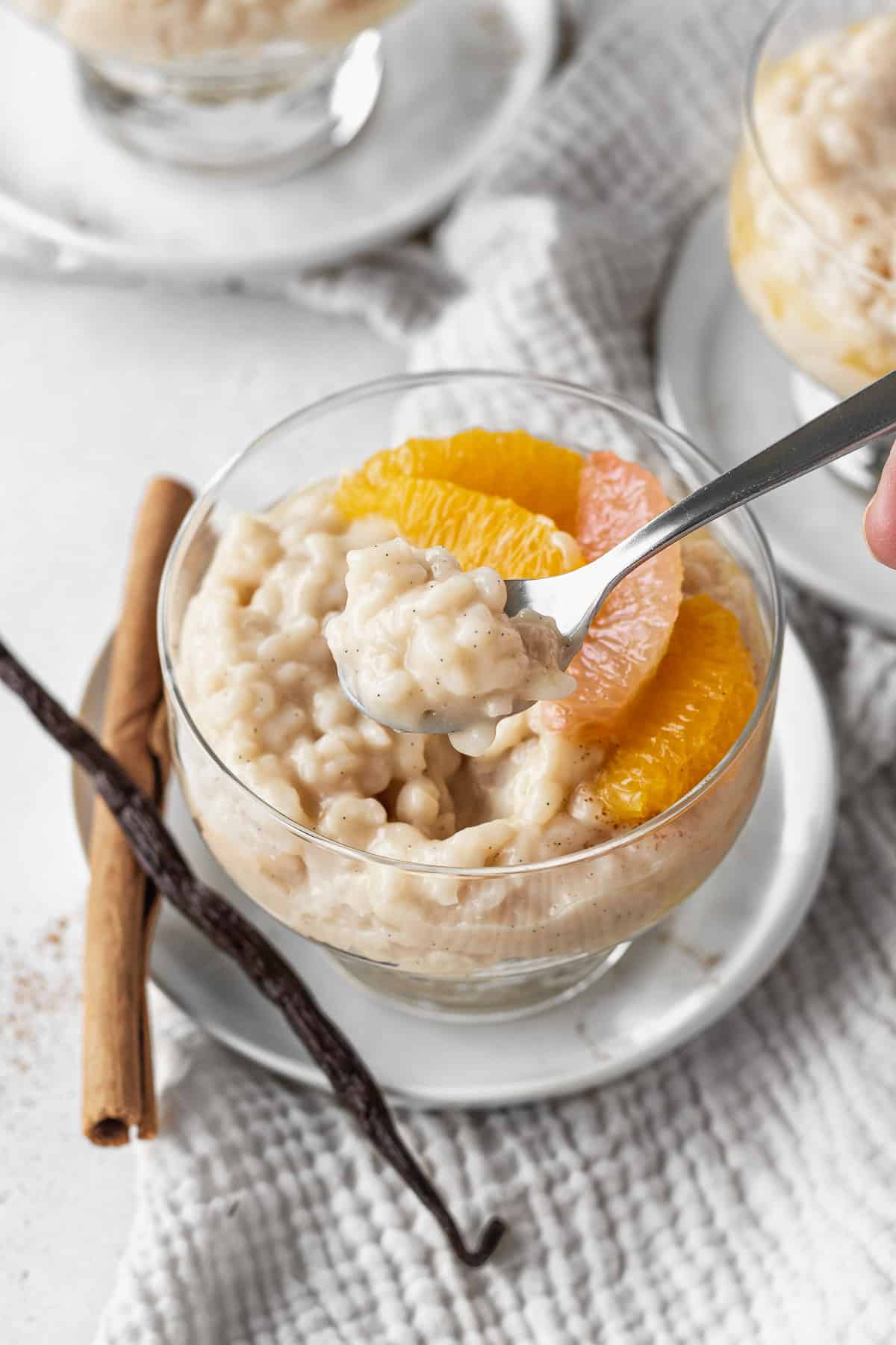 A spoonful of vegan rice pudding over a cup of the pudding.