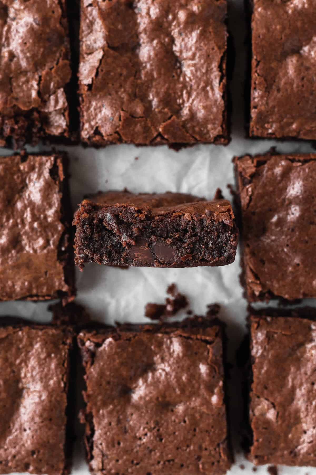 Gluten-free brownies cut into squares with the middle one turned onto its side edge to show the texture.