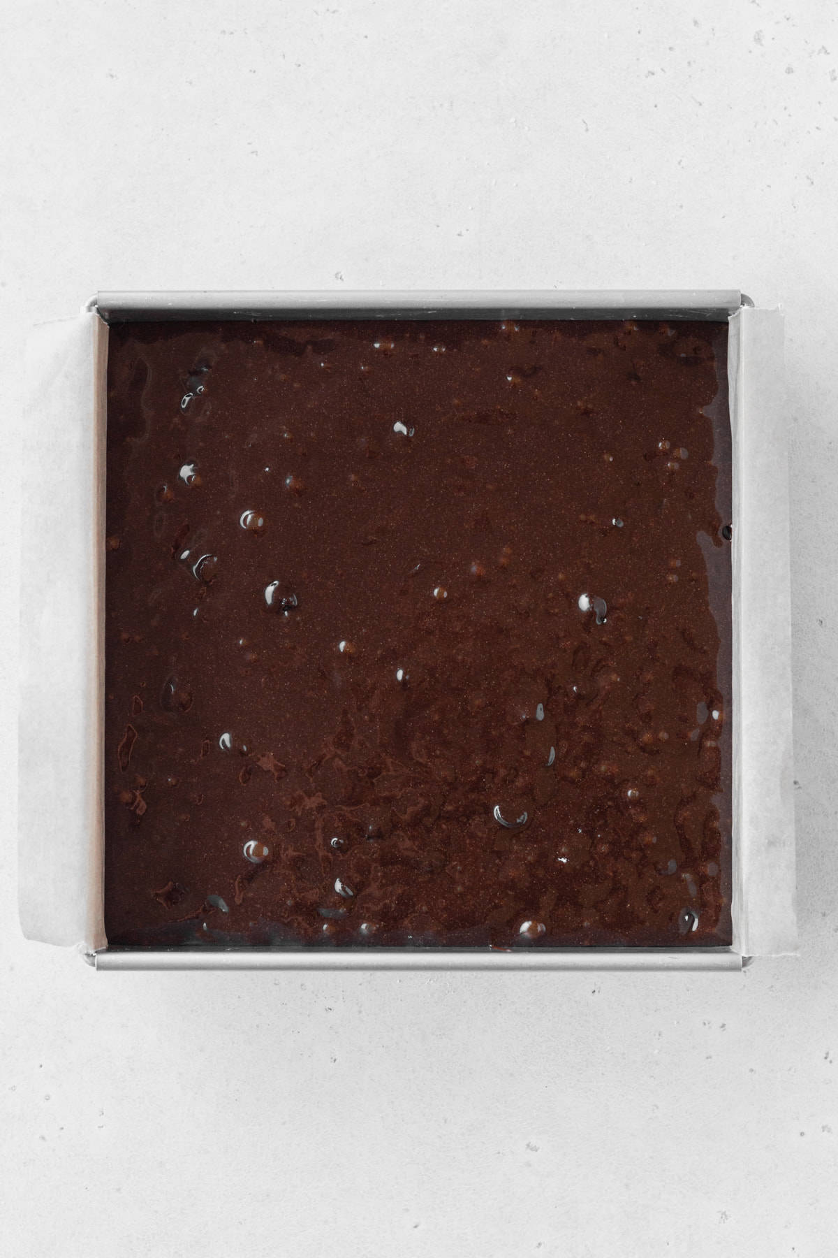 Gluten-free brownie batter poured into a square baking pan.