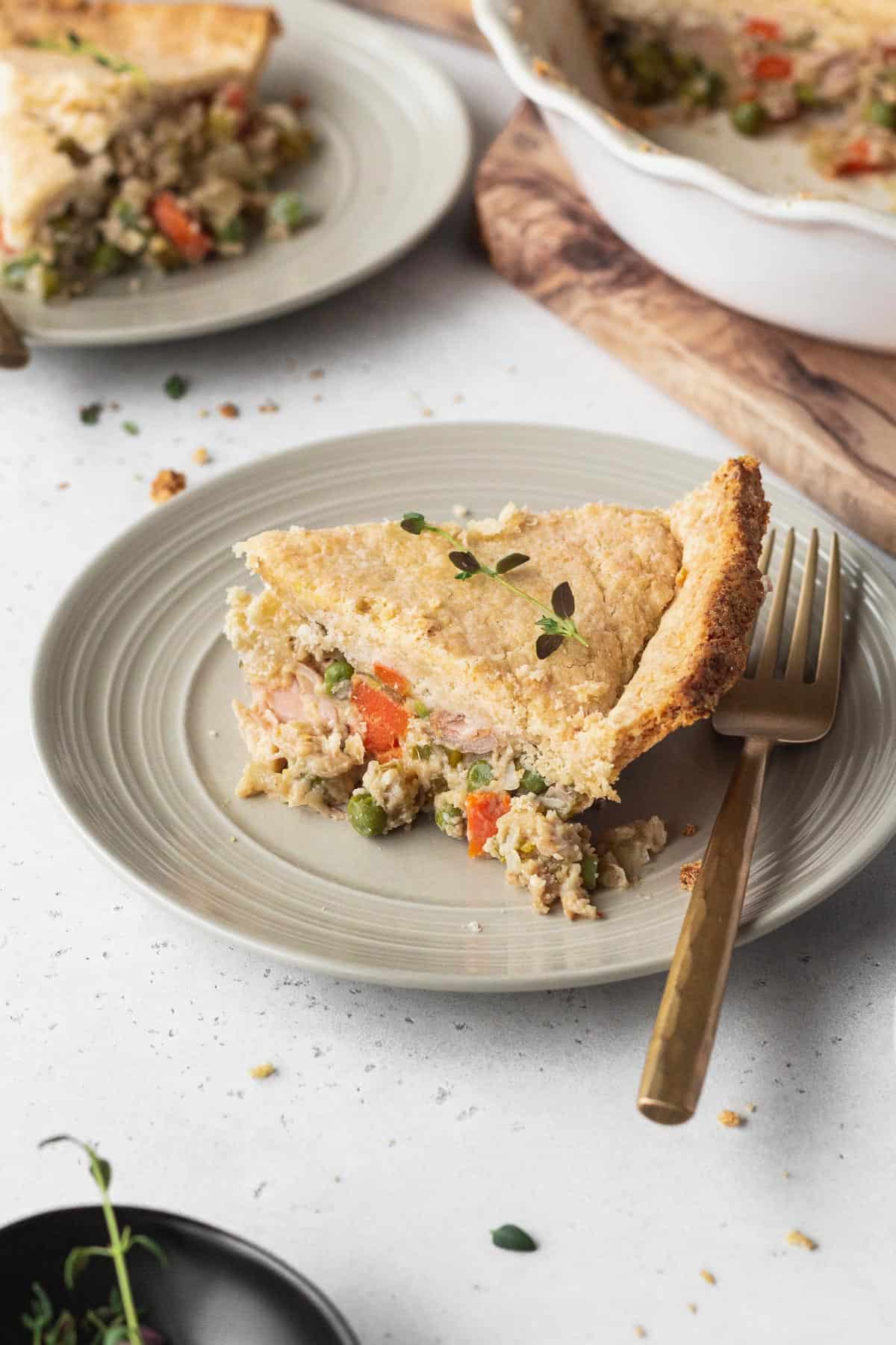 A slice of vegan pot pie on a plate with a gold fork.