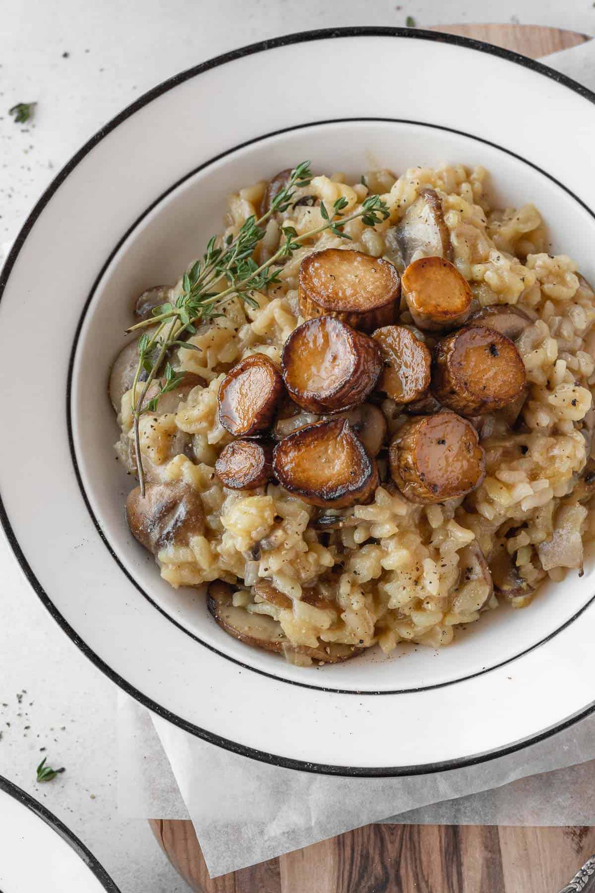 A plate of dairy free mushroom risotto with vegan scallops on top.
