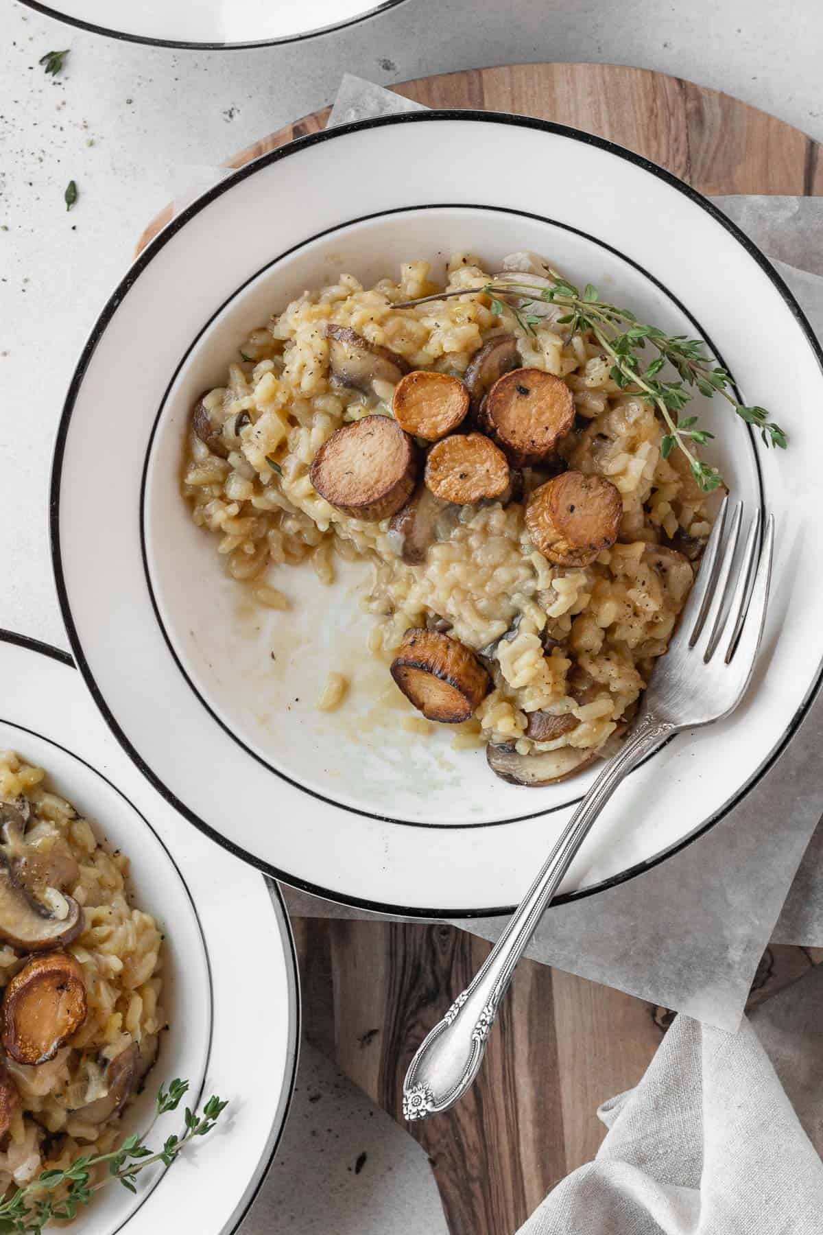 A half eaten plate of vegetarian risotto with vegan scallops on top.