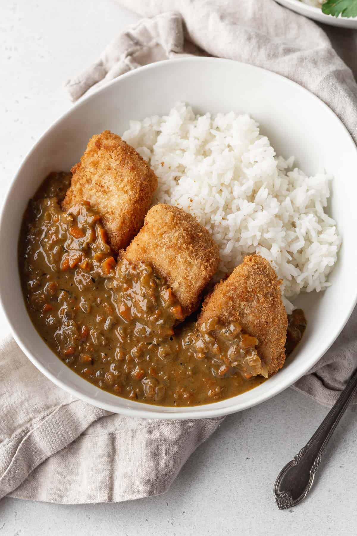 A bowl of white rice topped with katsu and vegan curry.