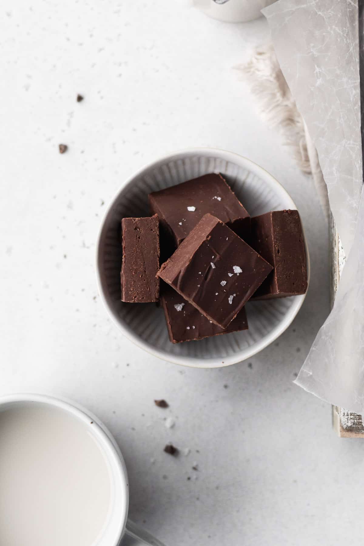 Overhead shot of cubes of dairy-free fudge in a white bowl on a white table.