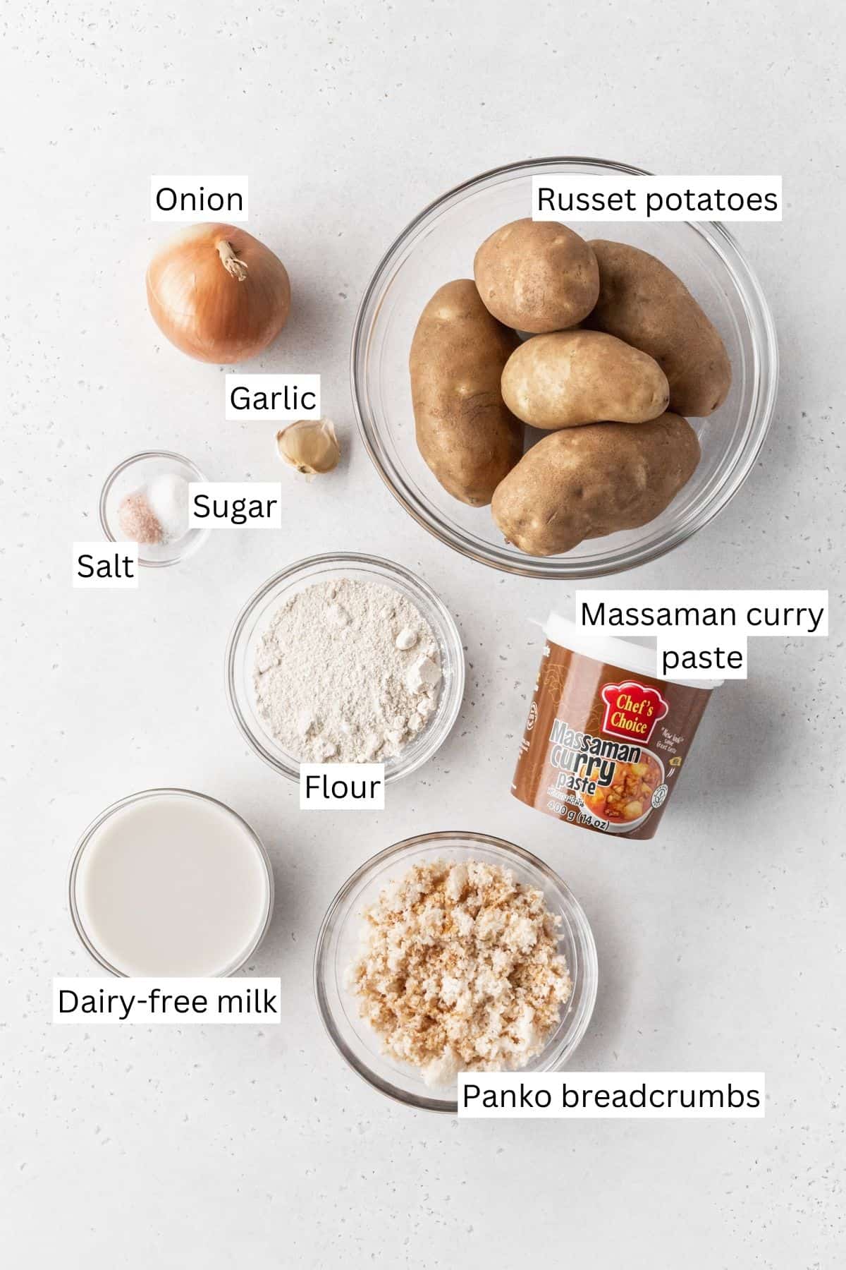 Ingredients for making vegan potato croquettes measured out into bowls on a white surface with text overlay.