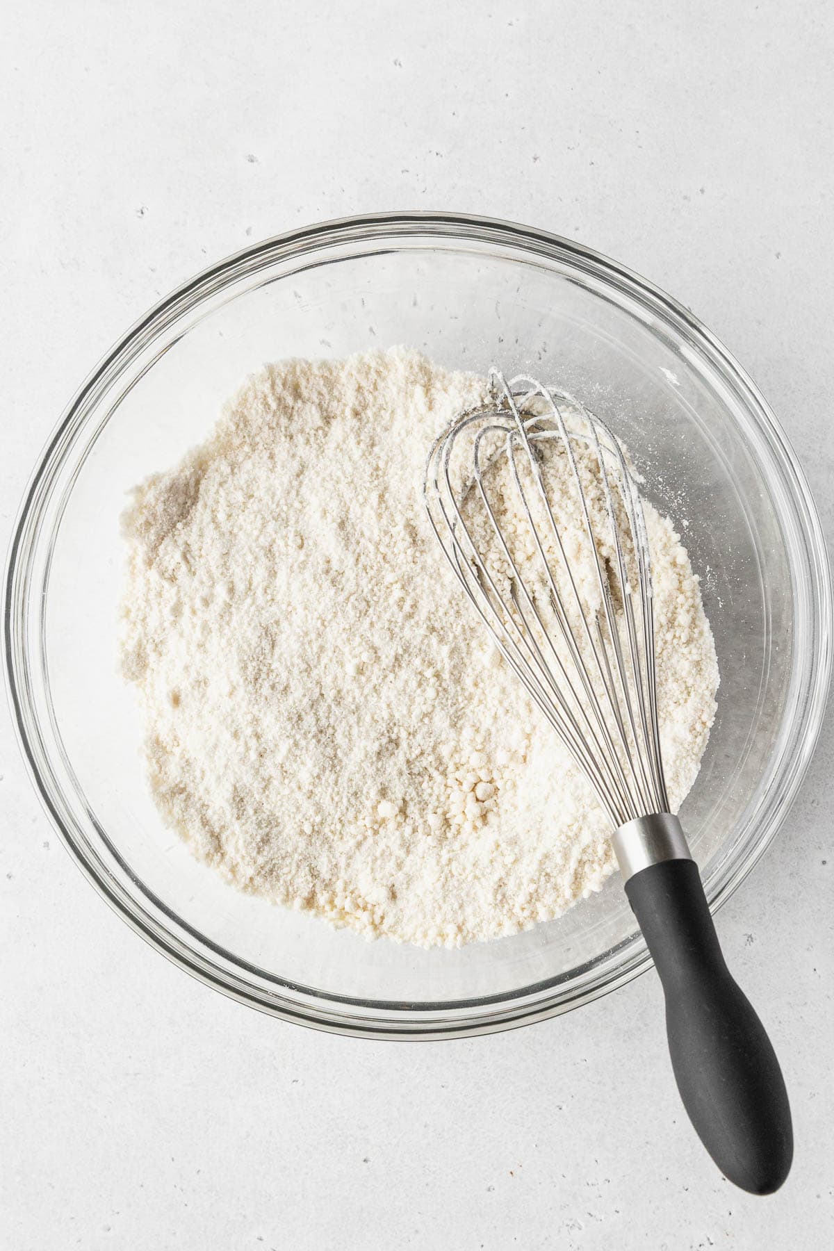 Dry ingredients whisked together in a clear glass mixing bowl.