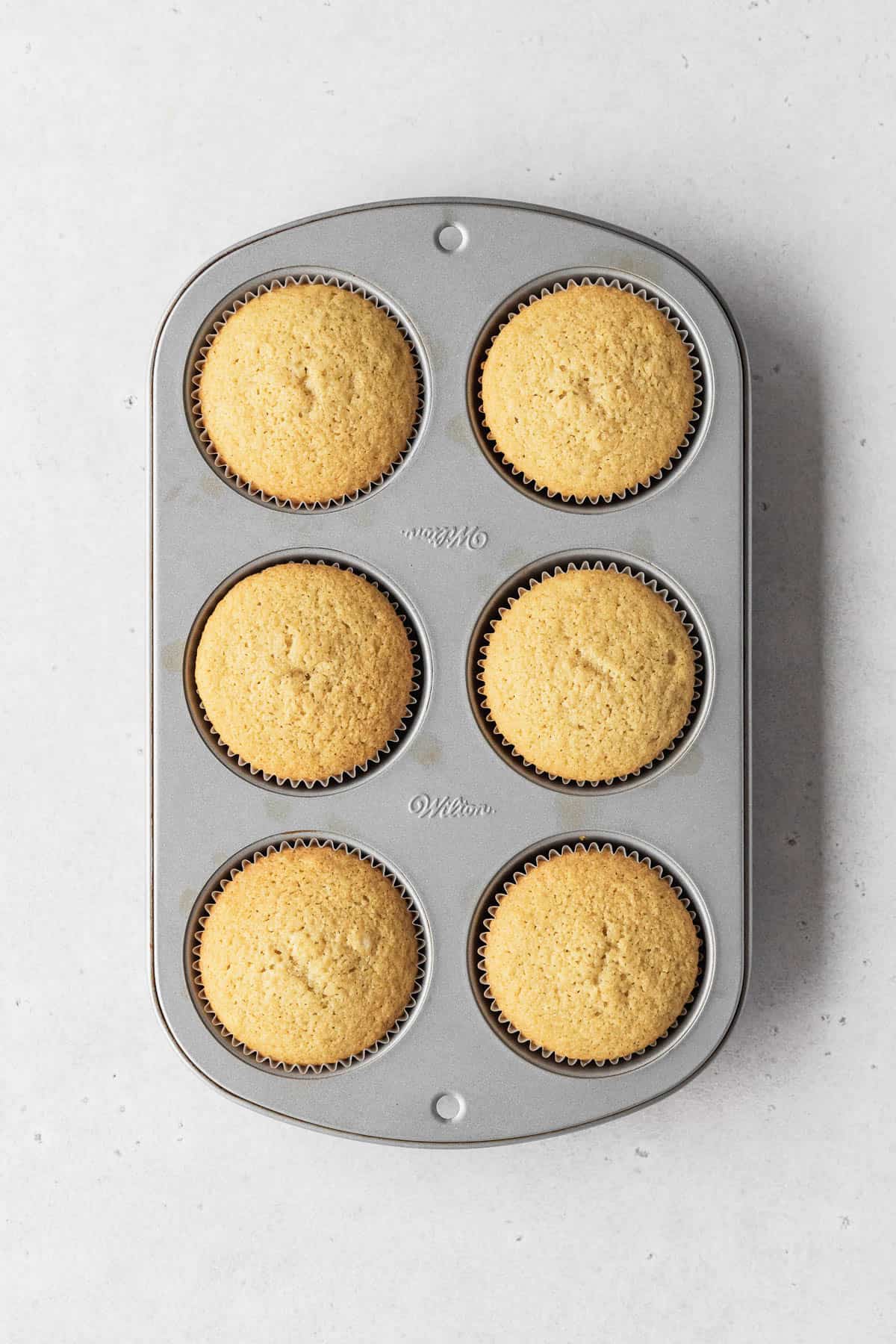 Muffin tin filled with 6 perfectly baked dairy-free vanilla cupcakes.
