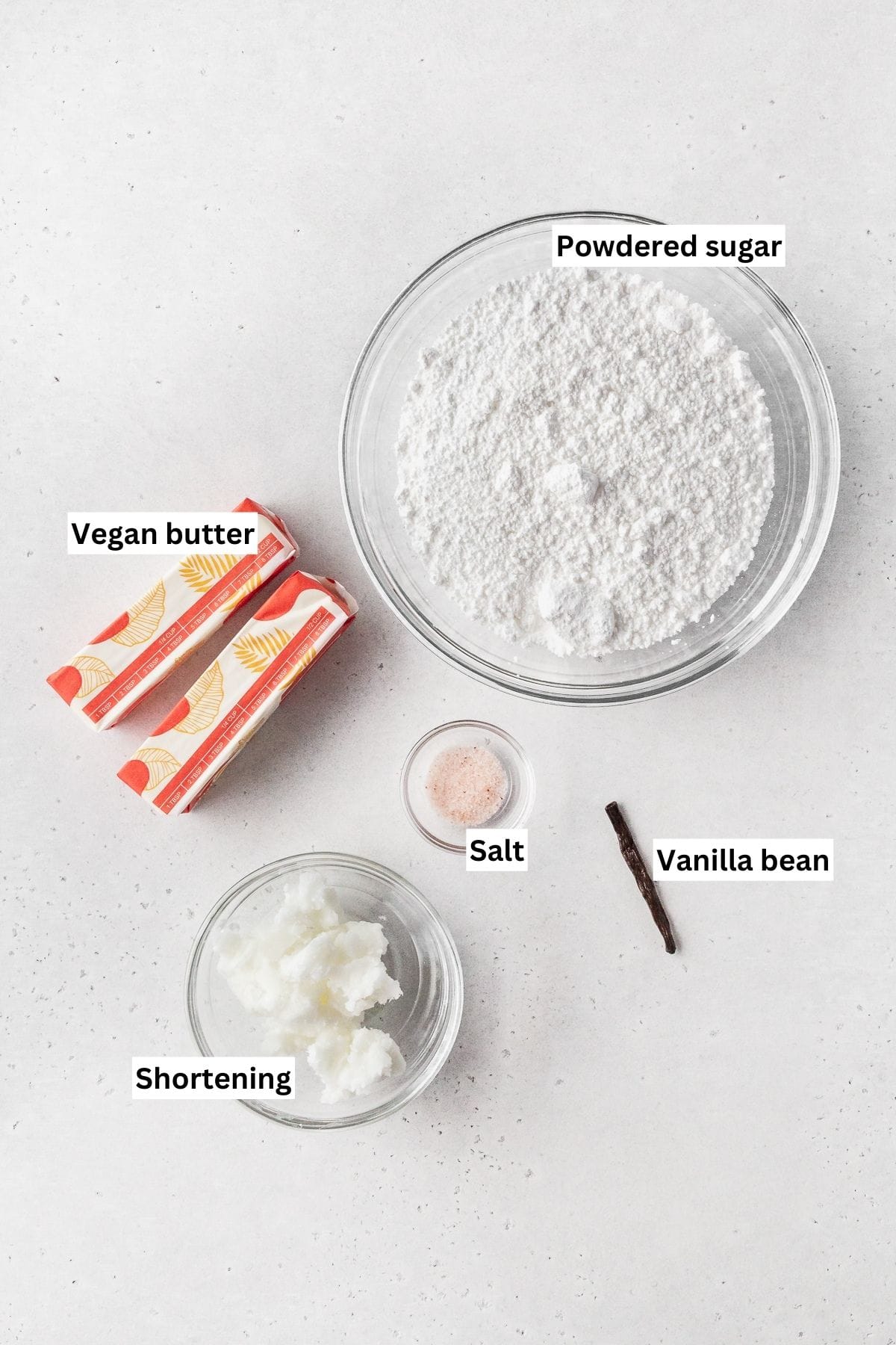 Ingredients for making vegan vanilla buttercream frosting laid out on a white table.