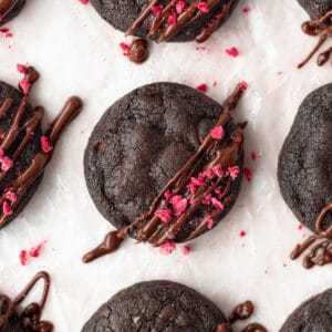 A close up shot of gluten-free double chocolate chip cookies with freeze-dried raspberries sprinkled on top.