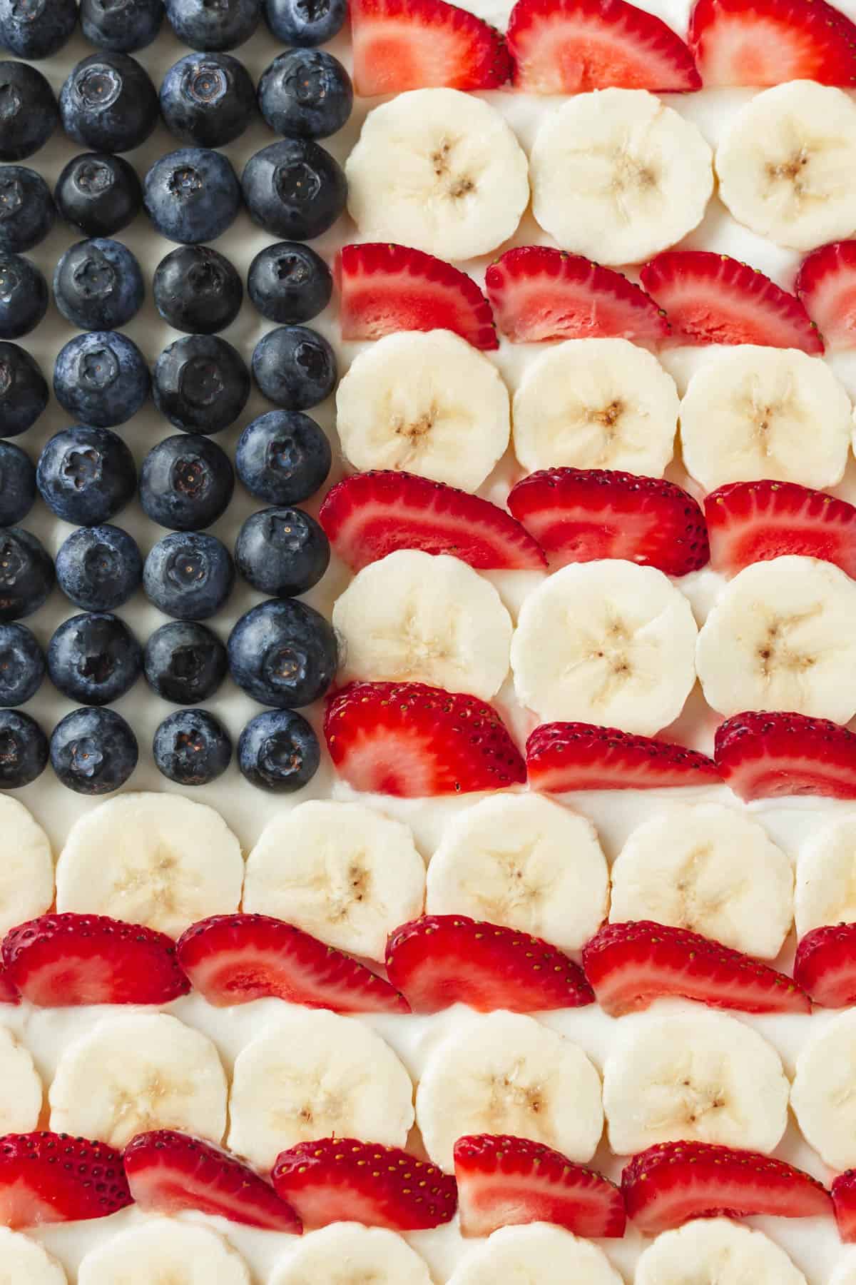 Blueberries, sliced bananas, and sliced strawberries arranged like the american flag on a sugar cookie "pizza."