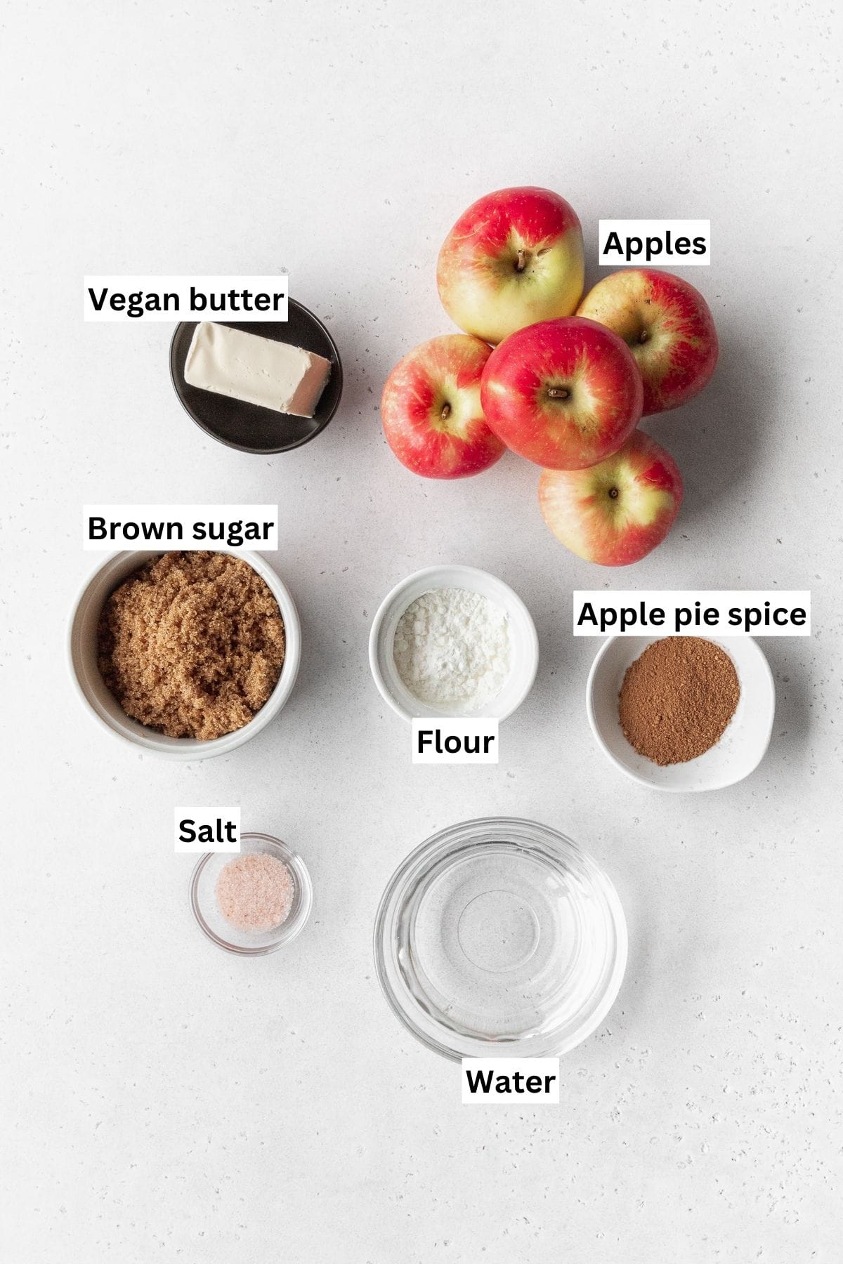 Overhead shot of apple pie filling ingredients measured into small bowls.