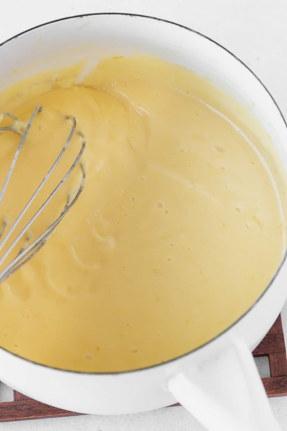 Cooking the dairy-free lemon curd in a white saucepan.