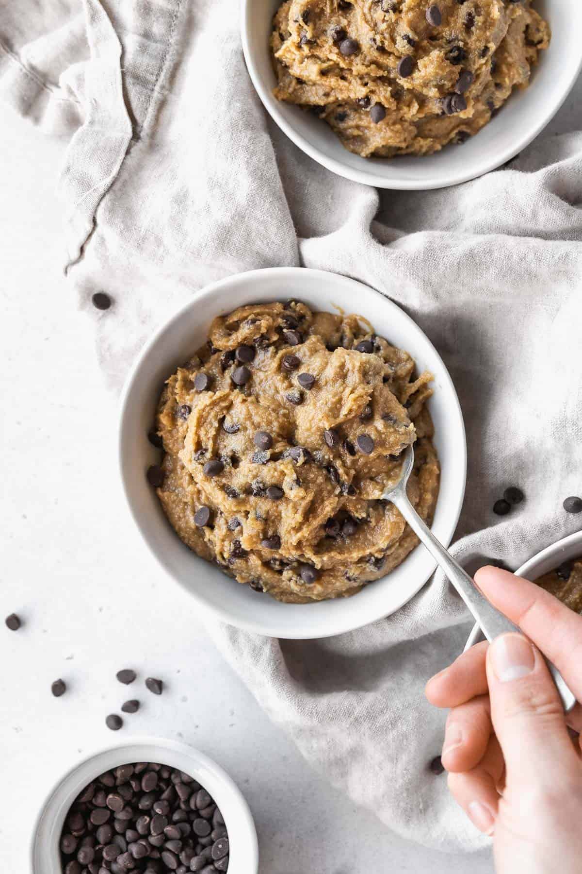 Hand taking a spoonful of dairy-free edible cookie dough from the bowl.