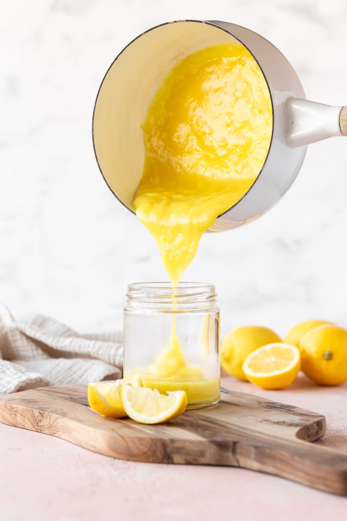 Pouring the vegan lemon curd from a saucepan into a mason jar.